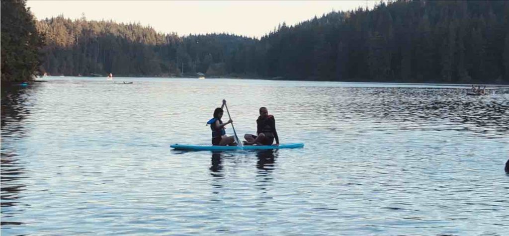 Father and daughter enjoying paddle-boarding at the famous White Pine Beach, Port Moody, Vancouver