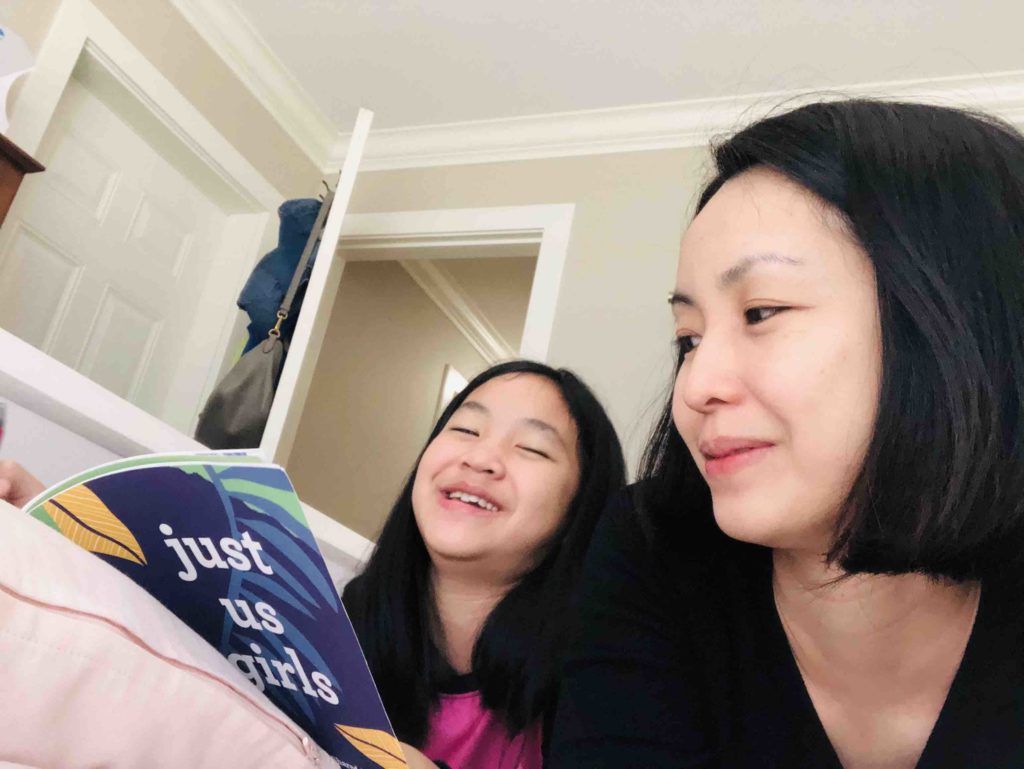 mother and daughter happily reading the book "just us girls"